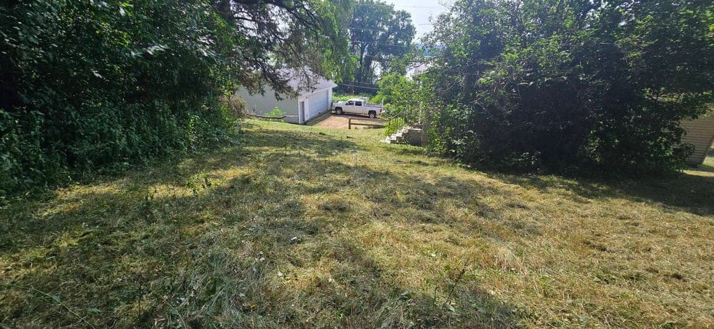 Freshly mowed residential lawn with crisp stripes beside a garage and truck